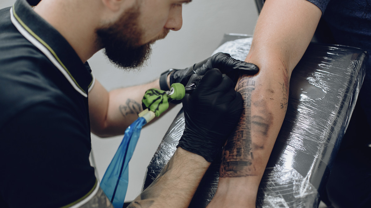 professionnel du tatouage travaillant sur le bras d'une personne
